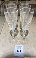 Six clear crystal champagne flutes standing on countertop