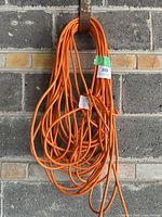 Coiled orange extension cord hanging on wall