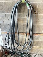 Full view of coiled grey hose hanging on wall