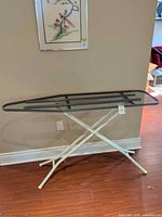 Side view of full ironing board showing mesh top and white X-legs