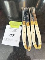 Three cheese cutters showing handles and bolsters with lot card