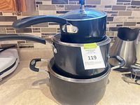 Stacked view of three black Lagostina pots with lids