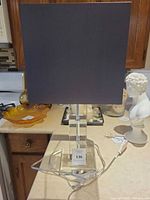 Full view of lamp with shade, clear lucite block base and cord visible