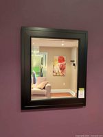 Front view of black framed rectangular mirror hanging on wall