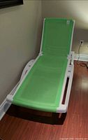 Full view of chaise showing white resin frame and green sling