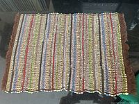 Single multicolour woven placemat showing stripe pattern and fringe