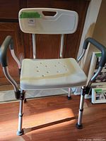 Front view of shower chair showing seat, backrest, armrests and adjustable legs