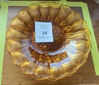 Deep amber pressed glass dish top view showing fluted edge and starburst bottom