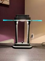 Front view of black metal two-column lamp with clear glass shade