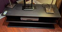 Front view of black wooden TV stand with two shelves