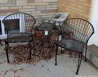 Two wrought iron armchairs flanking a slatted side table