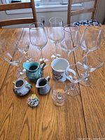 Overview of all glassware, ceramic creamers, mug, tumbler and porcelain floral figurine on table