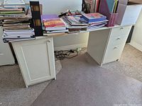 Front view of white IKEA desk showing cabinet, drawers, and wear