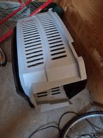 Grey vented top and black base of large plastic dog crate