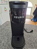 Front view of slim black Keurig coffee maker with drip tray and side water level indicator