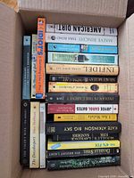 Open box showing two stacks of mixed hardcover and paperback books