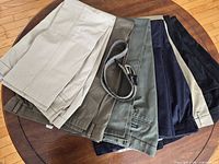 Seven pairs men’s pants in assorted colours with belt displayed