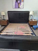 Front view of assembled bed frame showing headboard, side rails, slats, nightstands not included