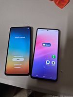 Two Samsung Galaxy A53 5G smartphones powered on; left shows welcome setup, right shows home screen