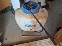 Front view of plastic sprayer tank showing SP1 marking, blue lid, attached spray wand