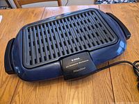 Top view of blue T-fal Slimline All Seasons electric grill showing grill plate, housing, handles and power cord