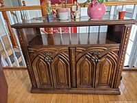 Front view of wooden bar/server showing overall design, carved doors, open upper shelf and top surface