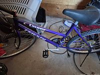 Full left-side view of purple Triumph bicycle showing frame, wheels, saddle and pedals
