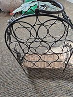 Overall view of metal wine rack showing circular bottle holders and wicker base
