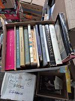 Box of assorted art and photography books showing spines