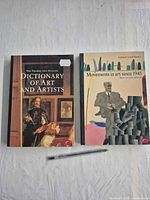 Front covers of both paperback books with pen for scale