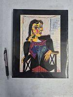 Front cover of Picasso exhibition softcover book beside pen for scale
