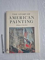 Front cover of hardcover book with dust jacket and pen for scale