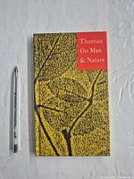 Front cover of hardcover book beside pen for scale