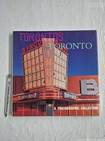 Front dust jacket with title and city photograph, pen for scale