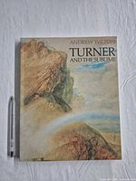 Front cover of large paperback book next to pen for scale