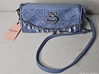 Front view showing full bag, tag, strap, decorative chain, heart logo