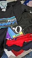 Stack of assorted shirts showing colors, graphics and Under Armour logo