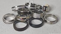 Ten assorted men’s stainless steel rings arranged on fabric surface