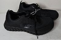 Side view of both black Skechers shoes