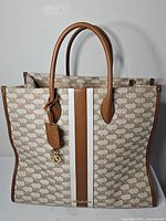 Front view of Michael Kors Mirella tote showing monogram canvas, leather trim, vertical stripes, MK charm