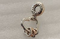 Front view of Pandora charm displaying open heart and rose-tone hearts