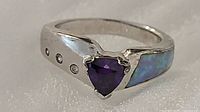 Front view showing purple triangle stone, clear accents, blue inlay