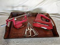 Overview of apple peeler, hand mixer with beaters on tray