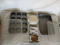 Overhead view of entire lot: muffin pan, baking pan, three storage bowls, plastic lids, boxed meat claws