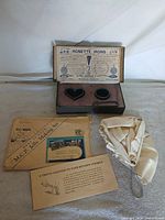 Group shot showing rosette iron set, MCP envelope, booklet, postcard, leaflet, and strainer bag