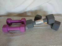 Two purple and two grey hex dumbbells side by side