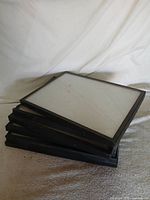 Stack of six black display frames showing black edges and glass fronts