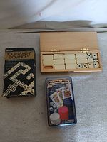 all three game sets side by side – wooden box open, dominoes box, playing cards chip set package