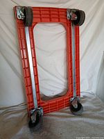 Underside view showing orange frame, steel supports, four swivel caster wheels