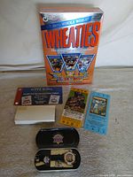 Group view: Wheaties cereal box, watch in tin, replica tickets, envelope